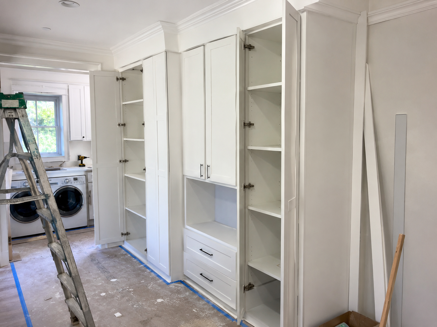 Pantry cabinet installation project with tall white shaker storage cabinets